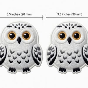 Peut inclure: Deux écussons brodés en forme de hibou, chacun mesurant 90 mm de large. Les hiboux sont blancs avec des détails noirs et gris, avec de grands yeux ronds jaune doré et des becs noirs. Les écussons ont un aspect cousu détaillé.