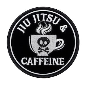 Op de afbeelding: Een ronde zwarte patch met witte tekst en een witte rand. De tekst luidt "JIU JITSU & CAFFEINE". In het midden staat een witte koffiekop met een schedel en gekruiste botten, met stoom die opstijgt.