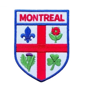 Può includere: Una toppa ricamata con un design a scudo blu, bianco e rosso. Lo scudo presenta una croce rossa con quattro simboli: un giglio blu, una rosa rossa, un cardo viola e un trifoglio verde. Il testo "MONTREAL" è scritto in blu nella parte superiore dello scudo.