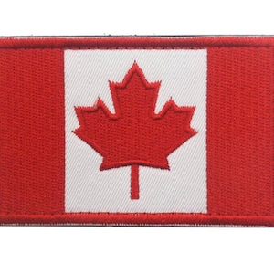 Op de afbeelding: Een geborduurde patch met de Canadese vlag met een rood esdoornblad op een witte achtergrond.