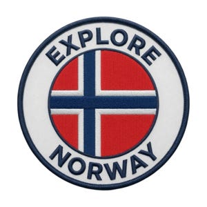 May include: A circular embroidered patch featuring the flag of Norway in the center with a red background, a blue cross, and white borders. The words EXPLORE are stitched in dark blue above the flag and NORWAY below on a white border.