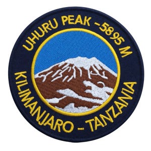 Può includere: Toppa ricamata rotonda con la scritta "UHURU PEAK -5895 M KILIMANJARO - TANZANIA". Raffigura un paesaggio montano con cielo blu, montagna marrone e neve bianca, con bordo blu navy e giallo.