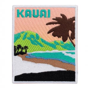 Op de afbeelding: Geborduurde patch met een tropische strandscène met het woord "KAUAI" in turquoise letters. Het ontwerp omvat een bruine palmboom, groene bergen en een blauwe oceaan onder een roze en oranje lucht. De patch heeft een witte rand.