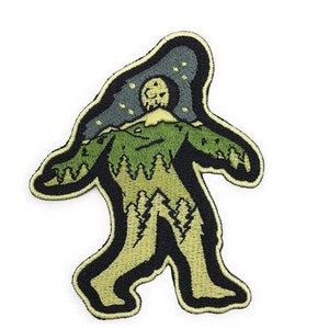 Puede incluir: Un parche bordado con la silueta de un Bigfoot verde y marrón con un cielo nocturno estrellado y una luna llena sobre su cabeza.