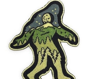 Könnte beinhalten: Ein gestickter Aufnäher mit der Silhouette eines grünen und braunen Bigfoots mit einem sternenklaren Nachthimmel und einem Vollmond über seinem Kopf.