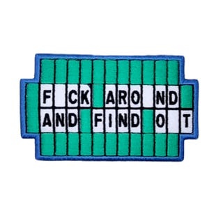 Può includere: Toppa ricamata con un design che ricorda un tabellone di un game show. La toppa presenta la frase "F*CK AROUND AND FIND OUT" in lettere bianche su sfondo verde e bianco, incorniciata da un bordo blu.