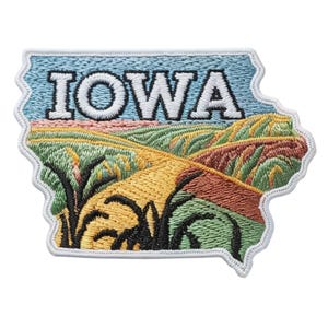 May include: Embroidered patch in the shape of Iowa, featuring a landscape of rolling hills in shades of green, yellow, and brown. The word "IOWA" is stitched in white block letters against a blue sky background.