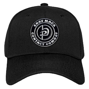 K&ouml;nnte beinhalten: Schwarze Baseballkappe mit einem wei&szlig;en gestickten Logo, auf dem "KRAV MAGA CONTACT COMBAT" mit einem stilisierten Symbol in der Mitte steht.