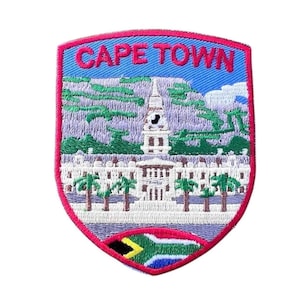May include: Embroidered patch with a red border, depicting a cityscape with a clock tower and the text "CAPE TOWN" in red letters. The bottom of the patch features the South African flag.