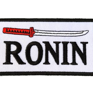 Könnte beinhalten: Weißer gestickter Aufnäher mit schwarzem Rand. Der Aufnäher zeigt ein rotes und weißes Schwert mit dem Wort "RONIN" in schwarzen Buchstaben.