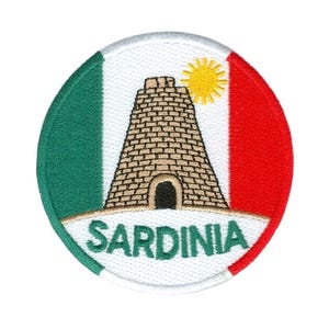 May include: Embroidered patch featuring the word "SARDINIA" below a brick tower and a yellow sun. The patch has a white border with green and red sections, resembling a flag.