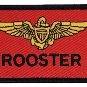 Peut inclure: Un écusson brodé rouge avec un insigne doré à ailes et le mot "ROOSTER" en lettres noires.