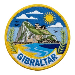 Op de afbeelding: Geborduurd embleem met een afbeelding van Gibraltar. Het ontwerp toont een berg, een kasteel, de zee en een gele zon. Het woord "GIBRALTAR" staat in blauwe letters in een boog onderaan, met een gele en blauwe rand.