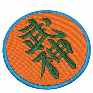 Pode incluir: Um remendo redondo de cor laranja com uma borda azul. O remendo apresenta um caractere kanji bordado em verde.