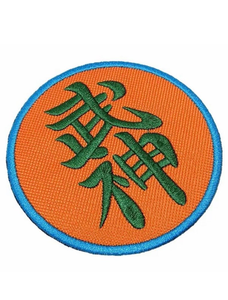 Pode incluir: Um remendo redondo de cor laranja com uma borda azul. O remendo apresenta um caractere kanji bordado em verde.