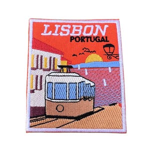 Könnte beinhalten: Ein gestickter Aufnäher mit orangefarbenem Hintergrund, der eine gelbe Sonne zeigt, die über einer Stadtlandschaft untergeht. Der Aufnäher trägt die Aufschrift "LISBON PORTUGAL" und zeigt eine braune und weiße Straßenbahn.
