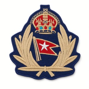 Op de afbeelding: Een marineblauwe geborduurde patch met een centrale rode zwaluwstaartvlag met een witte ster. De vlag wordt geflankeerd door twee beige lauriertakken en bekroond met een gedetailleerde kroon in rode, gouden en blauwe draad op een donkerblauwe achtergrond.