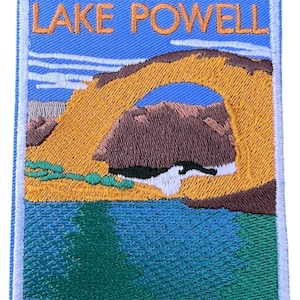Könnte beinhalten: Gestickter Aufnäher mit blauem Hintergrund und weißem Rand. Der Aufnäher zeigt einen gelben Torbogen mit blauem Himmel und weißen Wolken. Der Text "LAKE POWELL" steht in orangefarbenen Buchstaben oben auf dem Aufnäher.