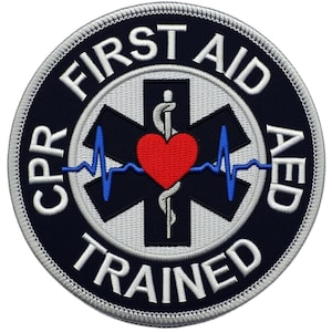 May include: Circular patch with the words "FIRST AID AED" and "CPR TRAINED" in white lettering on a navy blue background. A white cross-shaped emblem with a red heart and blue EKG lines is in the centre.