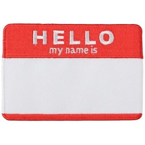 Op de afbeelding: Een rechthoekige naamlabel patch met een rood bovenstuk en een wit onderste gedeelte. Het woord "HELLO" is geborduurd in witte hoofdletters boven de zin "my name is". Het witte gedeelte is leeg en klaar voor personalisatie.