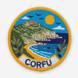 Op de afbeelding: Geborduurd ronde patch met een kustlandschap met een gebouw op een heuvel, een gele zon en het woord "CORFU". De patch heeft een gele rand, een blauwe lucht en een groen en bruin landschap.
