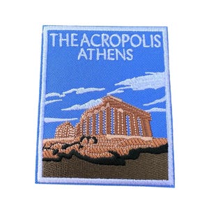 May include: Embroidered patch featuring a blue sky with white clouds, the Acropolis of Athens in brown and white, and the text "THE ACROPOLIS ATHENS" in white.