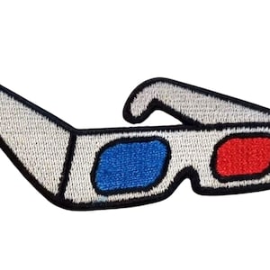 Peut inclure: Écusson brodé de lunettes 3D avec monture blanche et contours noirs. Les verres sont bleus et rouges. Le patch est conçu pour être repassé ou cousu sur du tissu.