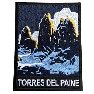 May include: Embroidered patch with a blue background featuring a mountain range with white clouds and the text "TORRES DEL PAINE" in white.