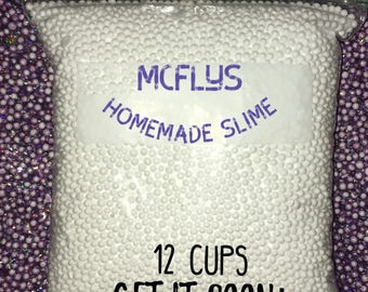 May include: A clear plastic bag filled with 120,000 white foam beads, labeled "MCFLYS HOMEMADE SLIME" and "12 CUPS GET IT SOON!"  The bag is sitting on a purple and white sparkly background.  The text "12 CUPS / 120,000 BEADS MADE IN AMERICA" is at the top of the image.