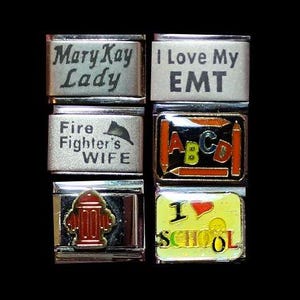 Könnte beinhalten: Satz von sechs silbernen Charms mit verschiedenen Designs. Die Charms beinhalten "Mary Kay Lady", "I Love My EMT", "Fire Fighter's Wife", "ABC", einen roten Hydranten und "I School".