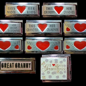 Puede incluir: Diez pulseras de charms plateadas con corazones rojos y varias inscripciones, incluyendo "This Mom Her Kids", "This Grandma Her Grand Kids", "This Grandma Her Grand Daughter", "This Grandma Her Grandson", "Special Aunt", "Special Friend", "Special Daughter", "Great Granny", y "I Love My Grandma".