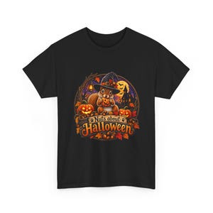 May include: A black short-sleeved t-shirt featuring a graphic of a squirrel wearing a witch hat and holding a small pumpkin. The design includes two jack-o'-lanterns, a haunted house, autumn leaves, and the text "Nuts about Halloween" in orange.