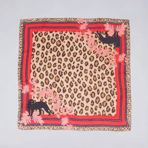 May include: A square scarf featuring a central leopard print pattern bordered by a thick red frame and a thin dark blue line. Two black panther silhouettes are positioned diagonally, surrounded by light pink foliage and light blue leaf accents.