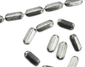 May include: A strand of silver-toned metal beads, with a few beads scattered around it. The beads are oval-shaped and have a brushed finish.