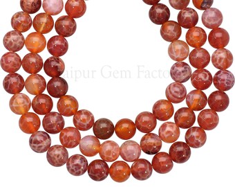 May include: A strand of carnelian agate beads, each bead is round and has a reddish-orange color with white and brown patterns.