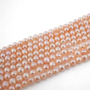 May include: A strand of pale pink freshwater pearls. The pearls are round and smooth, with a slight iridescent sheen.