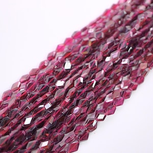 May include: A strand of faceted red garnet beads. The beads are a deep red colour and have a shiny, faceted finish. The beads are strung on a clear thread.