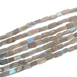 May include: Strands of rectangular, gray labradorite beads. The beads have a translucent quality with flashes of blue and iridescent hues. The beads are strung together, creating a textured and natural look. Ideal for jewelry making.