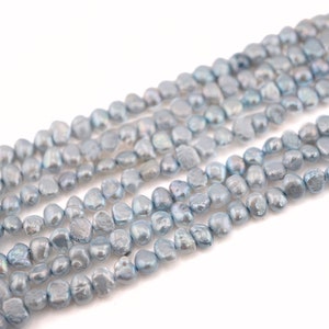 May include: A strand of light blue freshwater pearls, each pearl is irregular in shape and has a slightly iridescent sheen.