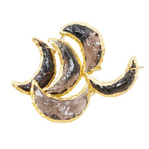 May include: A set of five gold-rimmed crescent moon-shaped pendants made of clear smoky quartz.
