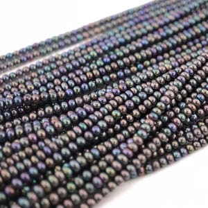 May include: A strand of iridescent black pearl beads. The pearls are small and round, with a subtle shimmer.
