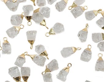 May include: A collection of raw, clear quartz crystal pendants with gold-colored metal caps and loops for jewelry making. The crystals have a rough, natural texture and vary in size and shape. The pendants are scattered against a white background.