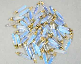 May include: A pile of light blue crystal point pendants with gold-toned jump rings. The pendants are approximately 1 inch long.