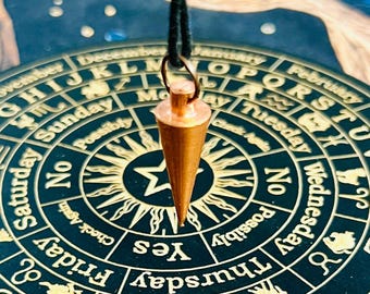 Könnte beinhalten: Ein goldfarbenes Pendel hängt über einem schwarzen und goldenen Kreisdiagramm mit Wochentagen, Sternzeichen und den Wörtern "Ja", "Nein" und "Möglicherweise" am Rand.