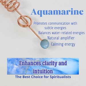 May include: A copper-colored wand with a light blue aquamarine stone at the tip. The word "Aquamarine" is displayed in blue text, along with text that reads "Promotes communication with subtle energies" and "Enhances clarity and intuition."