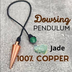 Pode incluir: Um pêndulo de radiestesia de cobre com uma ponta pontiaguda, pendurado em um cordão preto com uma conta de jade verde. O texto "Dowsing Pendulum" e "100% COPPER" é visível na imagem.