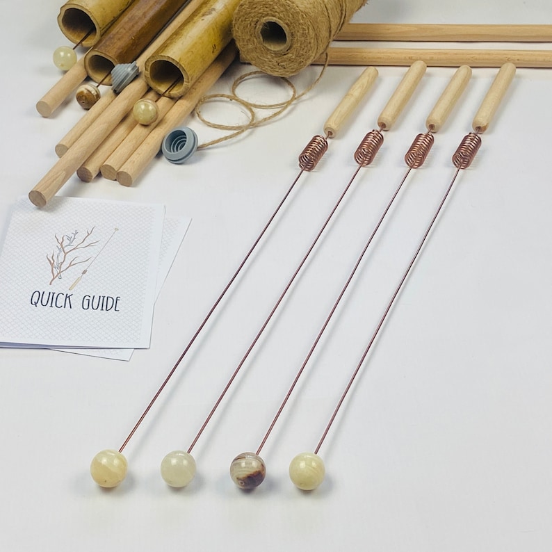 May include: Four wooden sticks with copper wire coils and different colored stone tips. The sticks are on a white surface with a card that says "Quick Guide".