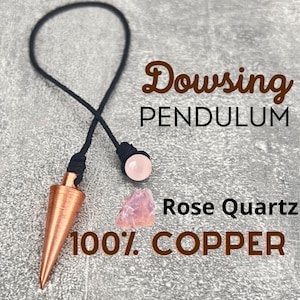 Può includere: Un pendolo per radiestesia in rame con una punta di cristallo di quarzo rosa. Il pendolo è attaccato a un cordino nero ed è etichettato "Pendolo per radiestesia 100% RAME Quarzo rosa".