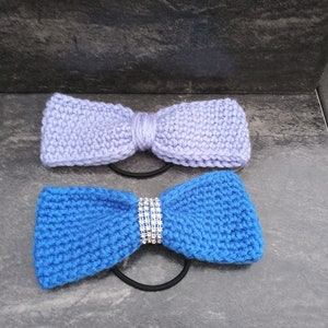 May include: Two knitted hair ties, one light purple and one blue, with a rhinestone embellishment on the blue hair tie.