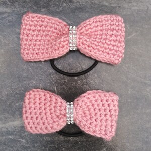 May include: Two pink crocheted hair scrunchies with a rhinestone embellishment.